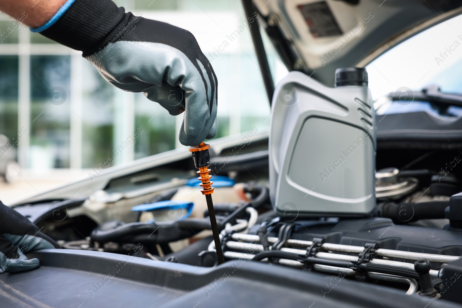 Worker checking motor oil level in car with dipstick, closeup Photo of Worker checking motor oil level in car with dipstick, closeup