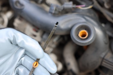 Photo of Worker checking motor oil level in car with dipstick, closeup