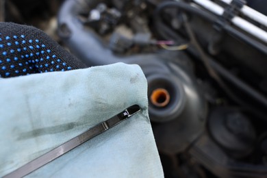 Photo of Worker checking motor oil level in car with dipstick, closeup