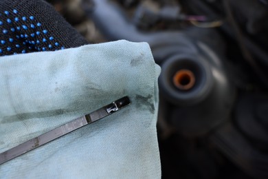 Photo of Worker checking motor oil level in car with dipstick, closeup
