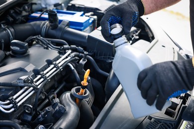 Photo of Worker checking motor oil level in car with dipstick, closeup