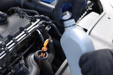 Photo of Worker checking motor oil level in car with dipstick, closeup