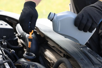 Photo of Worker checking motor oil level in car with dipstick, closeup