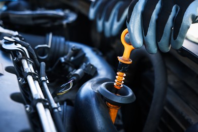 Photo of Worker checking motor oil level in car with dipstick, closeup