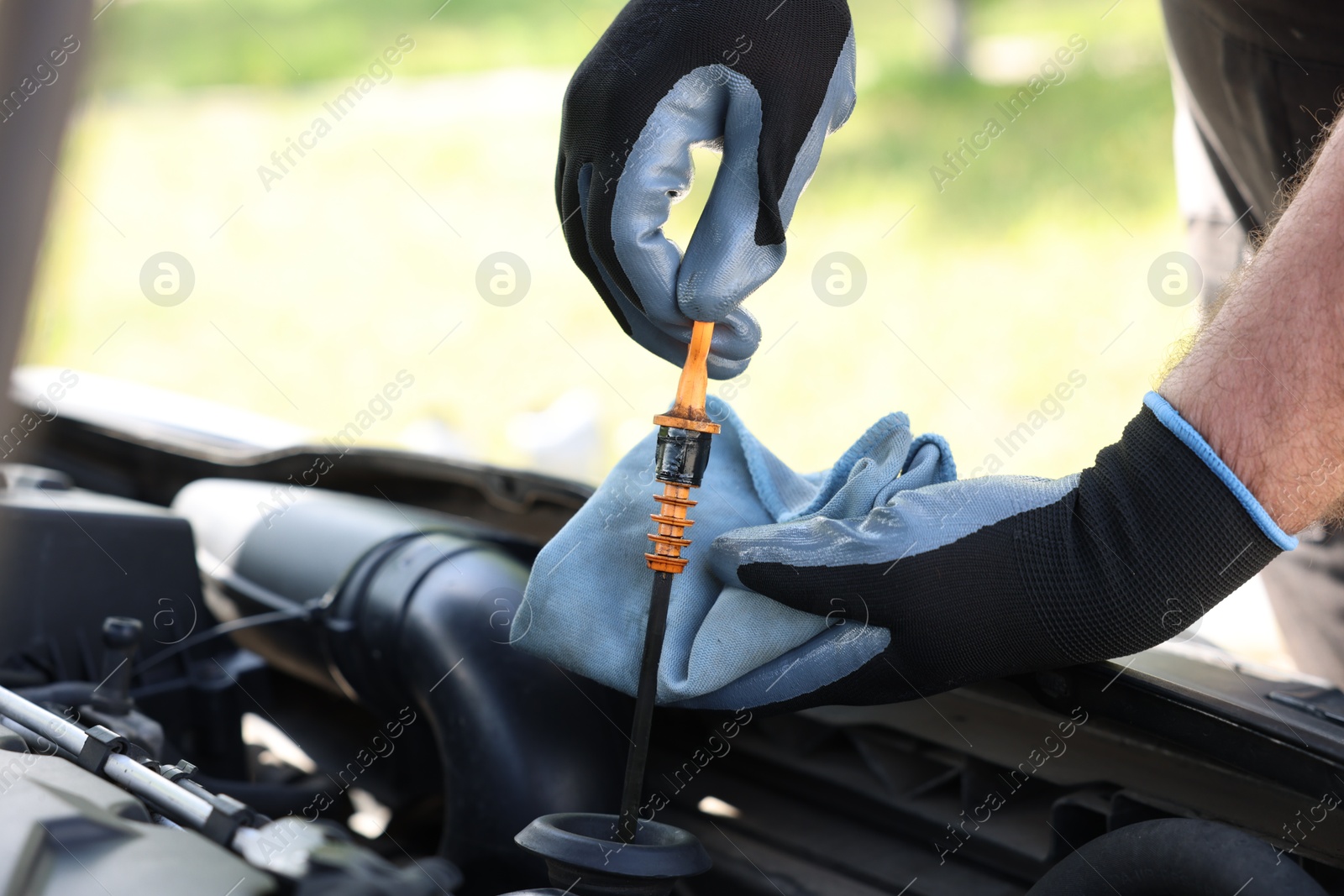 Worker checking motor oil level in car with dipstick, closeup Photo of Worker checking motor oil level in car with dipstick, closeup