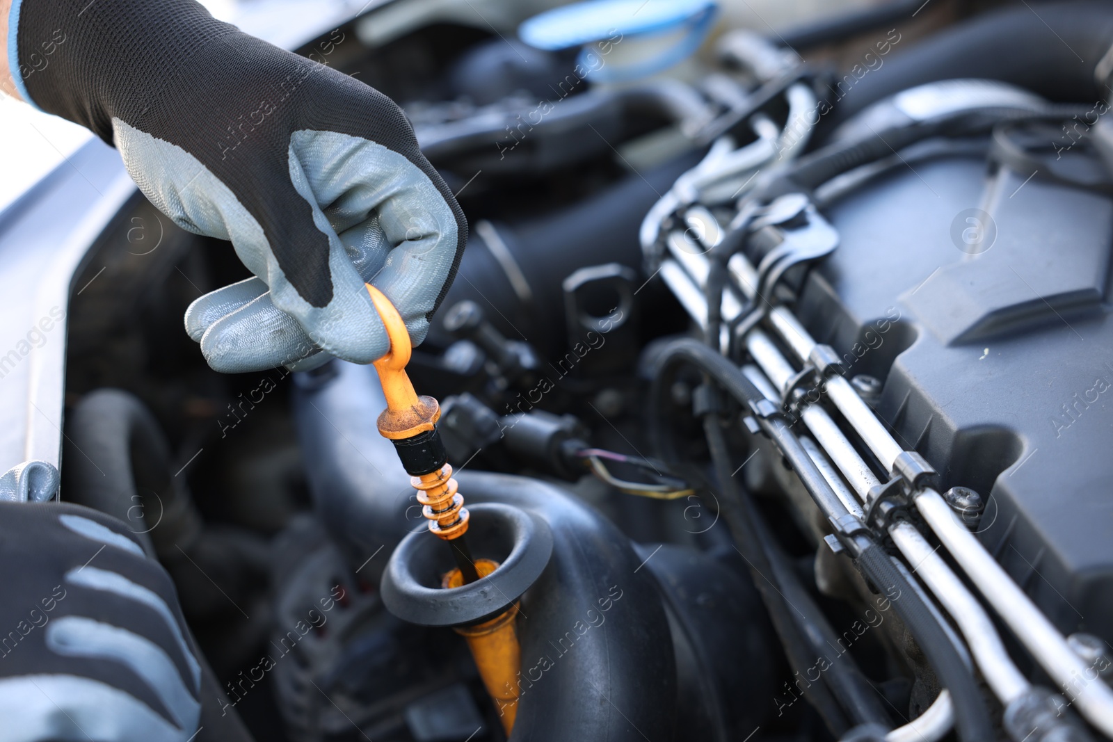 Worker checking motor oil level in car with dipstick, closeup Photo of Worker checking motor oil level in car with dipstick, closeup
