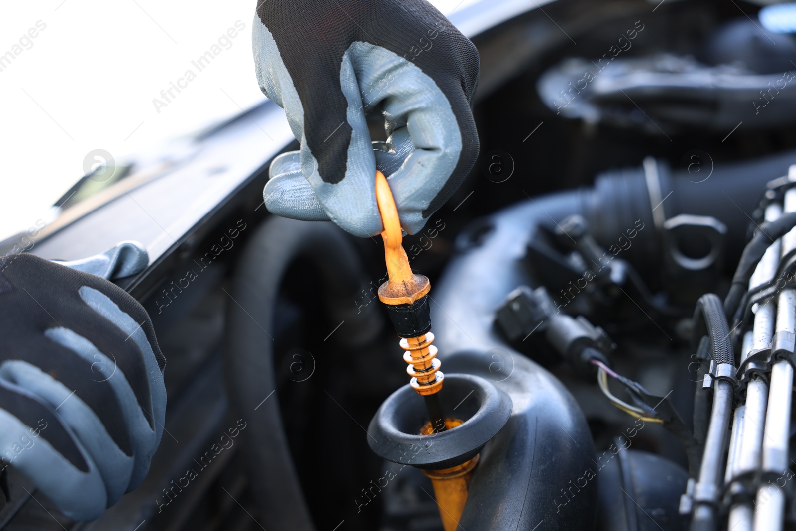 Worker checking motor oil level in car with dipstick, closeup Photo of Worker checking motor oil level in car with dipstick, closeup