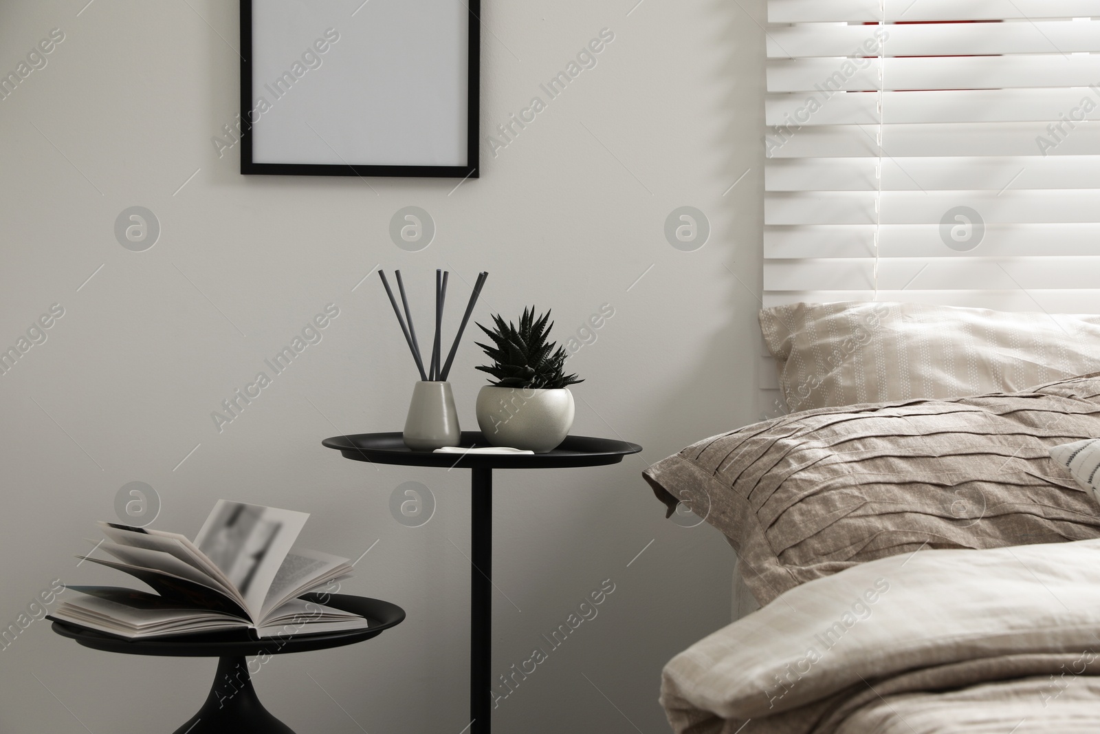 Comfortable bed with beautiful linens, nesting tables and decor in bedroom Photo of Comfortable bed with beautiful linens, nesting tables and decor in bedroom