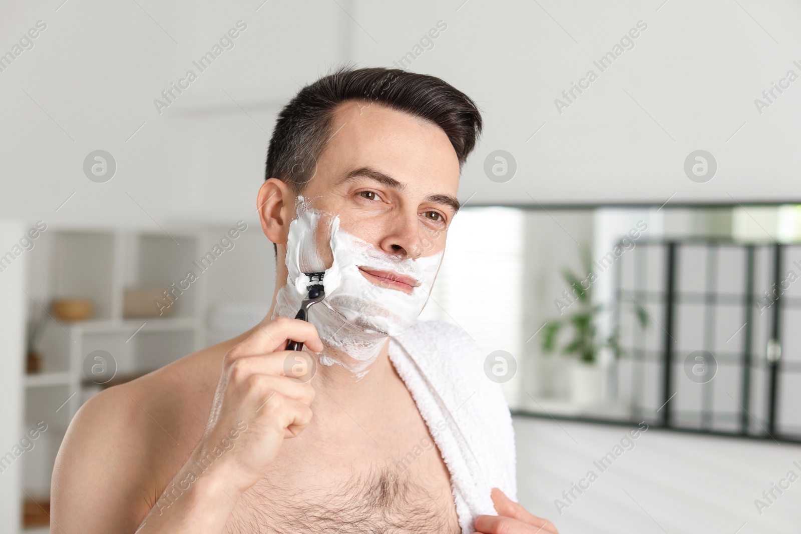 Handsome man shaving with razor at home Photo of Handsome man shaving with razor at home