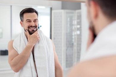 Photo of Smiling man before shaving looking at mirror in bathroom