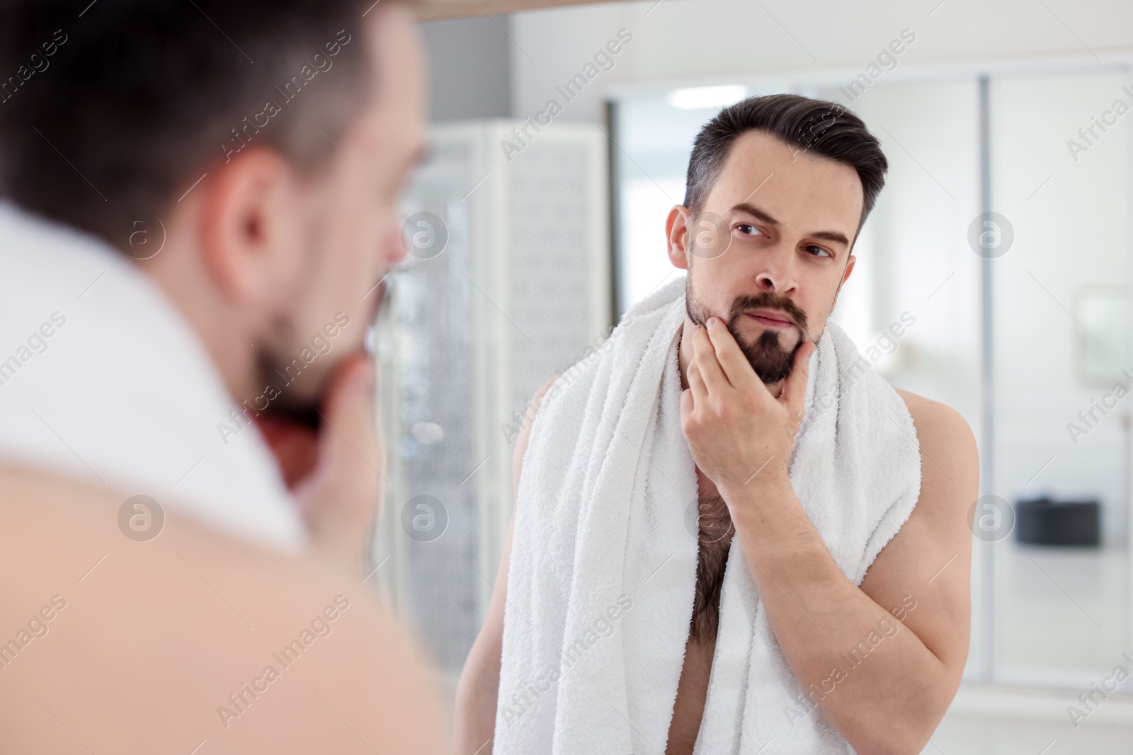 Handsome man before shaving looking at mirror in bathroom Photo of Handsome man before shaving looking at mirror in bathroom