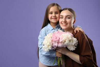 Photo of Mother and her daughter with bouquet of beautiful peonies on purple background