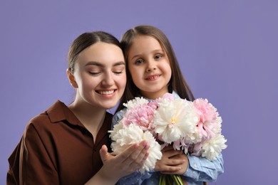 Photo of Mother and her daughter with bouquet of beautiful peonies on purple background