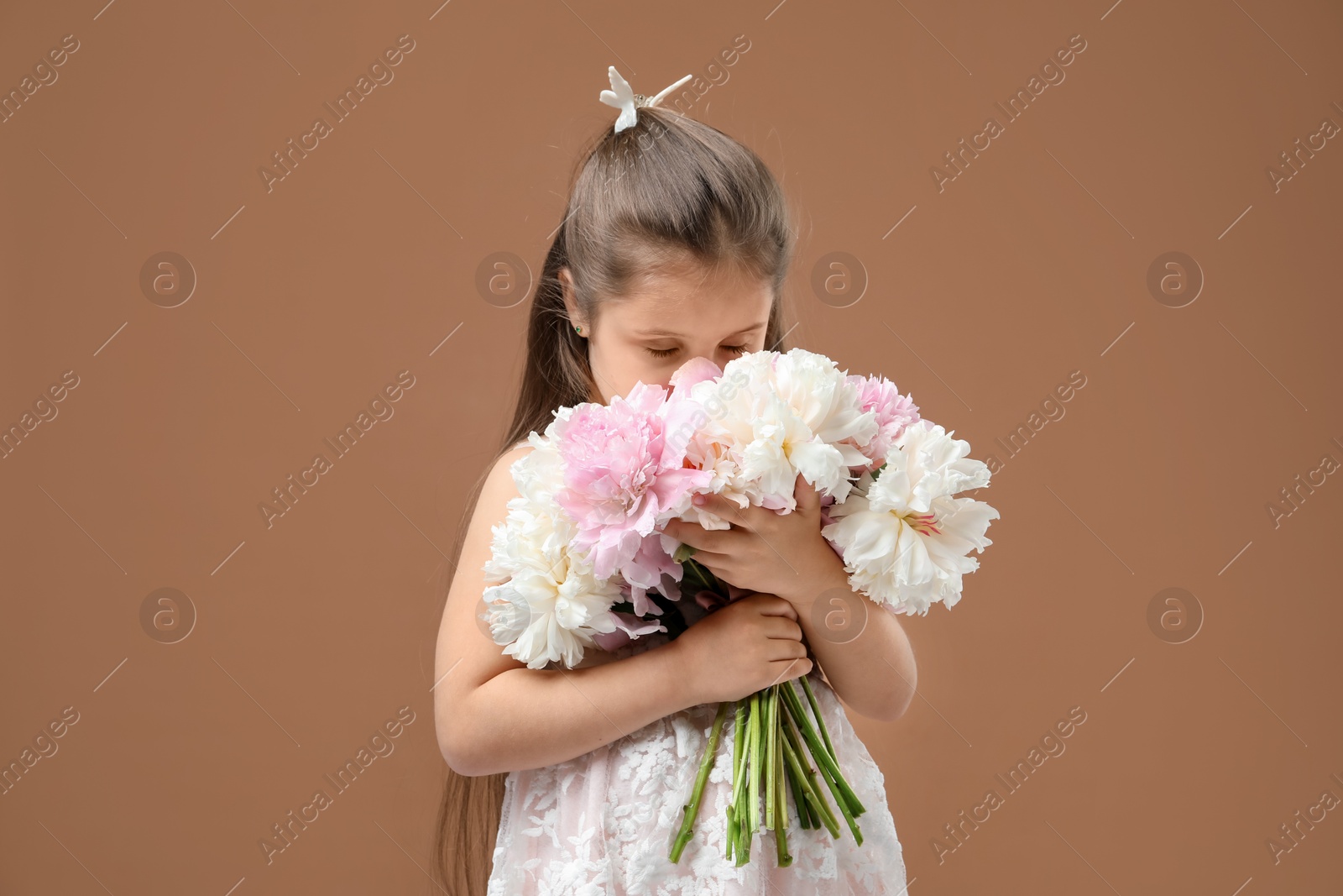 Cute little girl with bouquet of beautiful peonies on brown background Photo of Cute little girl with bouquet of beautiful peonies on brown background