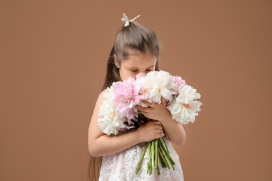 Photo of Cute little girl with bouquet of beautiful peonies on brown background