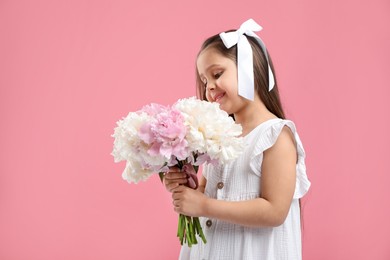 Photo of Cute little girl with bouquet of beautiful peonies on pink background