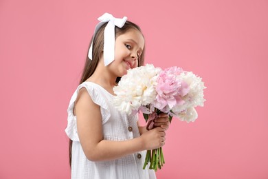 Photo of Cute little girl with bouquet of beautiful peonies on pink background