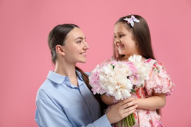 Photo of Mother and her daughter with bouquet of beautiful peonies on pink background