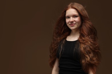 Photo of Portrait of beautiful teenage girl with healthy wavy hair on brown background. Space for text