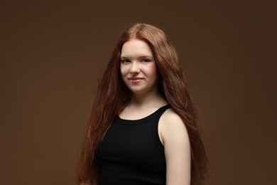 Photo of Portrait of beautiful teenage girl with healthy wavy hair on brown background