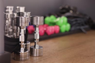 Photo of Many dumbbells on floor in fitness studio, closeup. Space for text