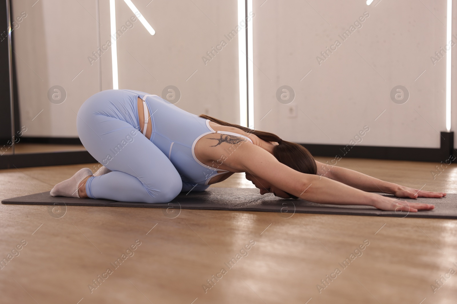Woman stretching on mat in fitness studio Photo of Woman stretching on mat in fitness studio