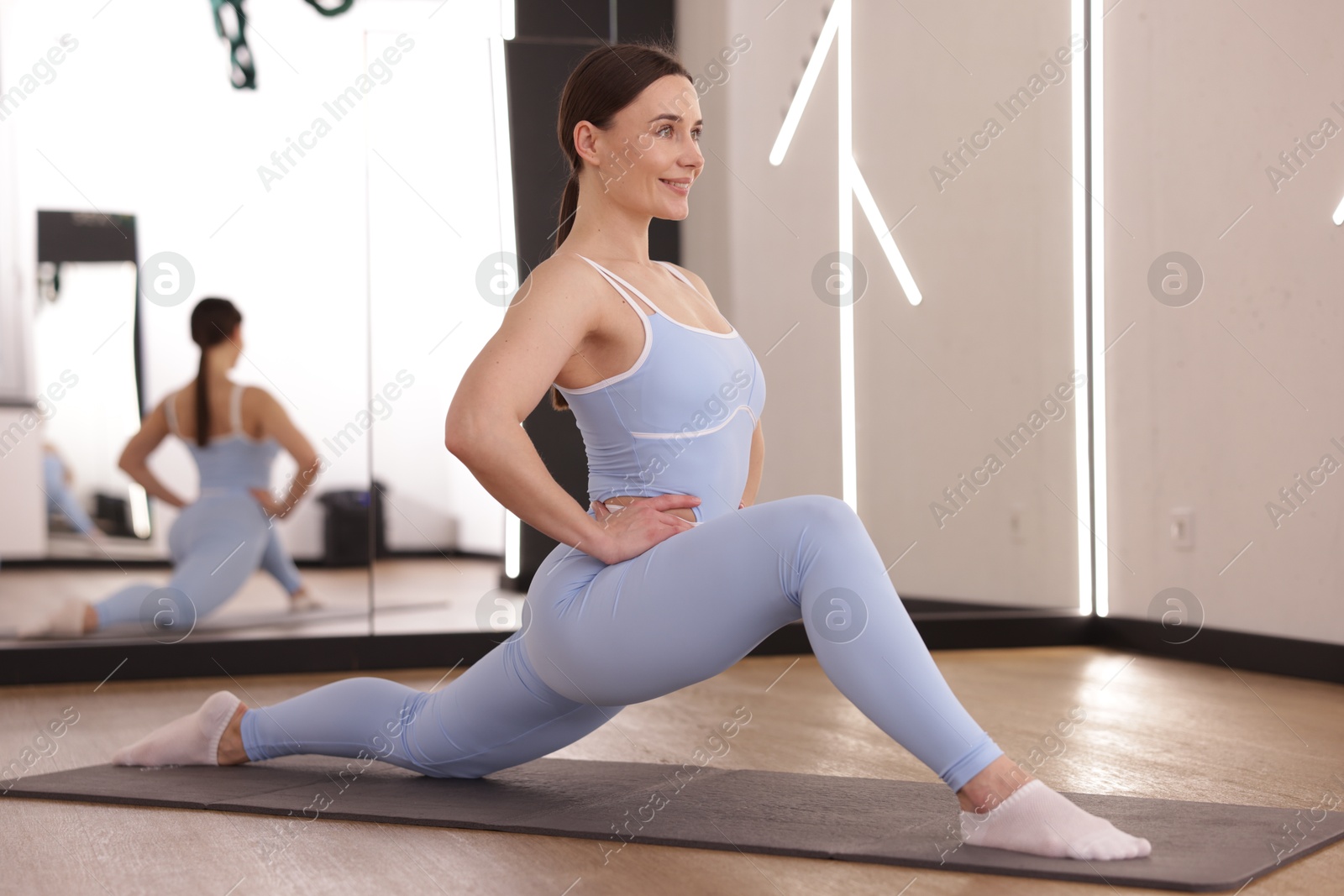 Photo of Woman stretching on mat in fitness studio