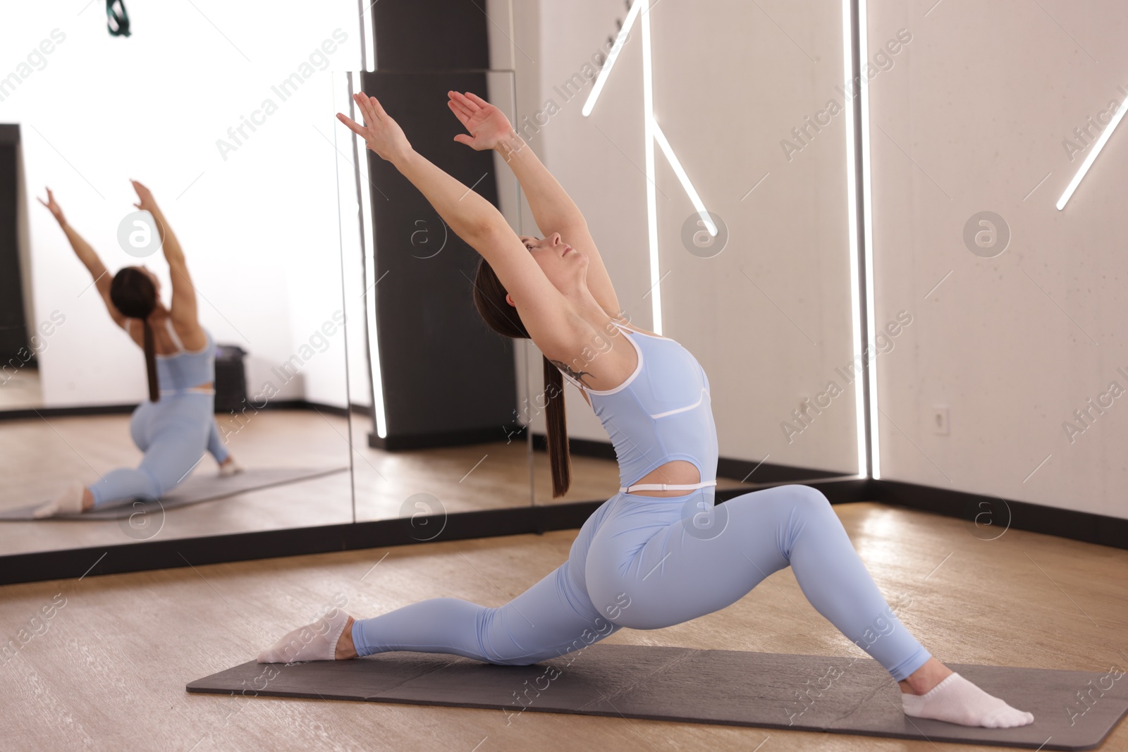 Woman stretching on mat in fitness studio Photo of Woman stretching on mat in fitness studio