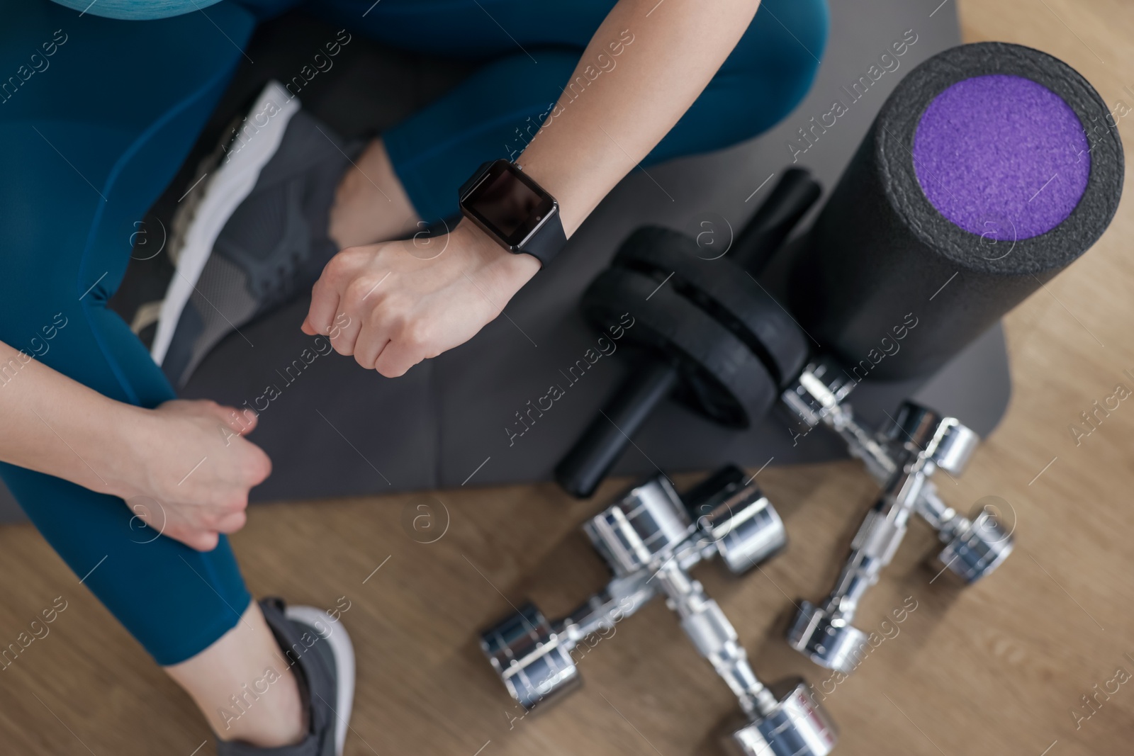 Woman checking fitness tracker during training indoors, top view Photo of Woman checking fitness tracker during training indoors, top view