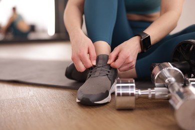 Photo of Woman tying shoelaces on floor in fitness studio, closeup. Space for text