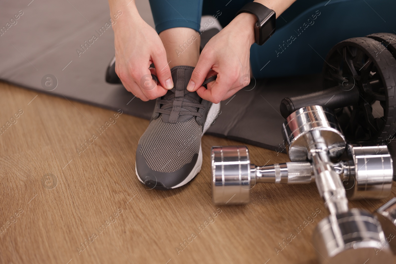 Woman tying shoelaces on floor in fitness studio, closeup Photo of Woman tying shoelaces on floor in fitness studio, closeup