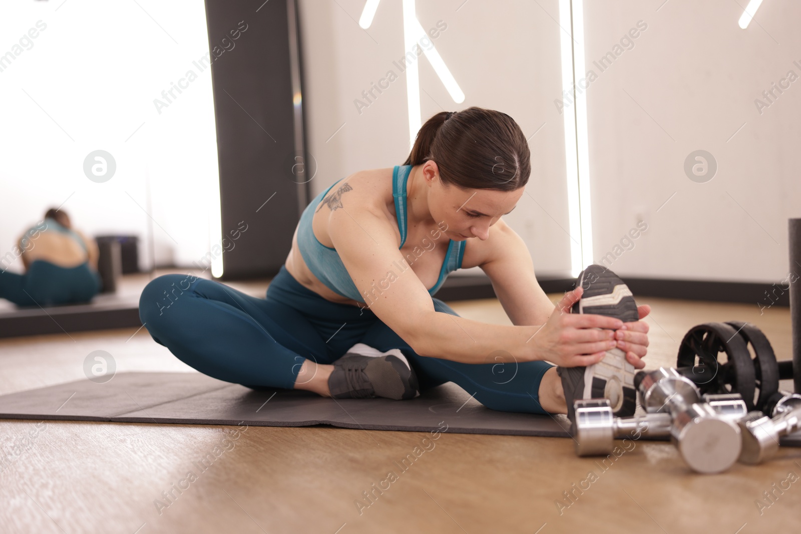 Woman stretching on mat in fitness studio Photo of Woman stretching on mat in fitness studio