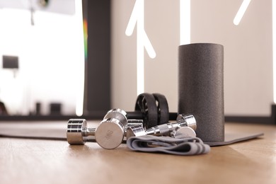 Photo of Dumbbells, elastic band, foam roller and mat on floor in fitness studio