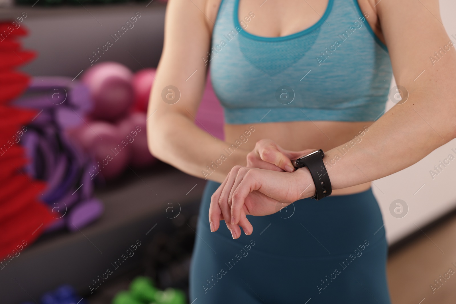 Woman checking fitness tracker during training indoors, closeup. Space for text Photo of Woman checking fitness tracker during training indoors, closeup. Space for text