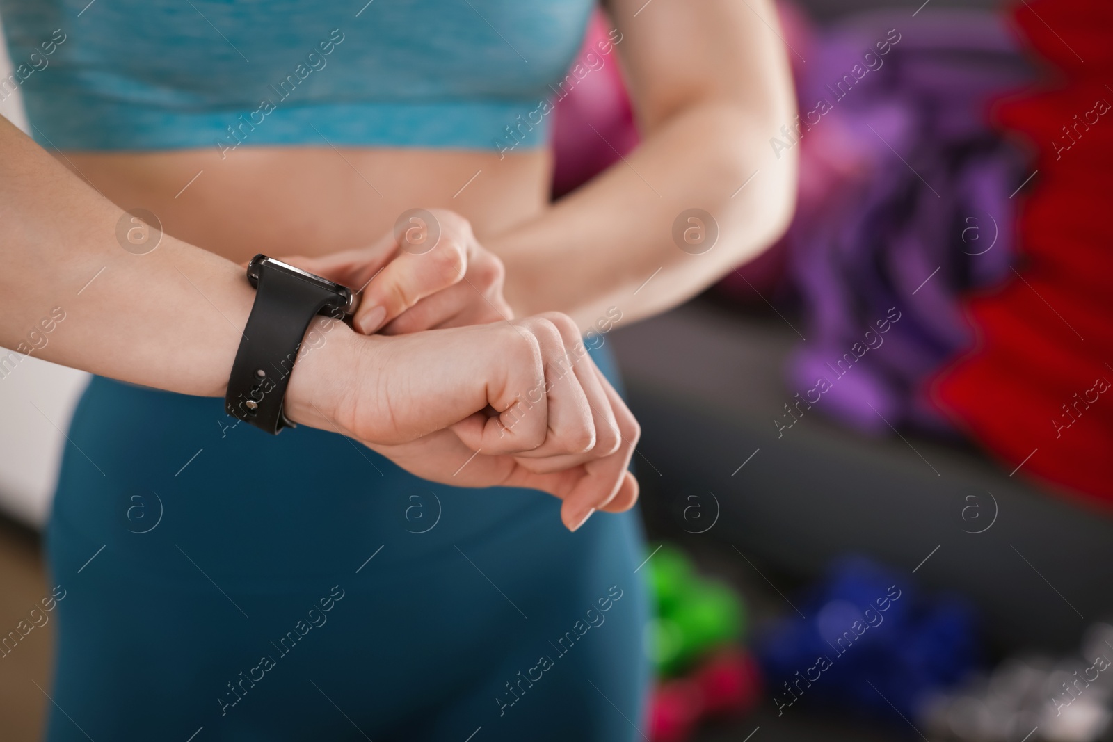 Woman checking fitness tracker during training indoors, closeup. Space for text Photo of Woman checking fitness tracker during training indoors, closeup. Space for text