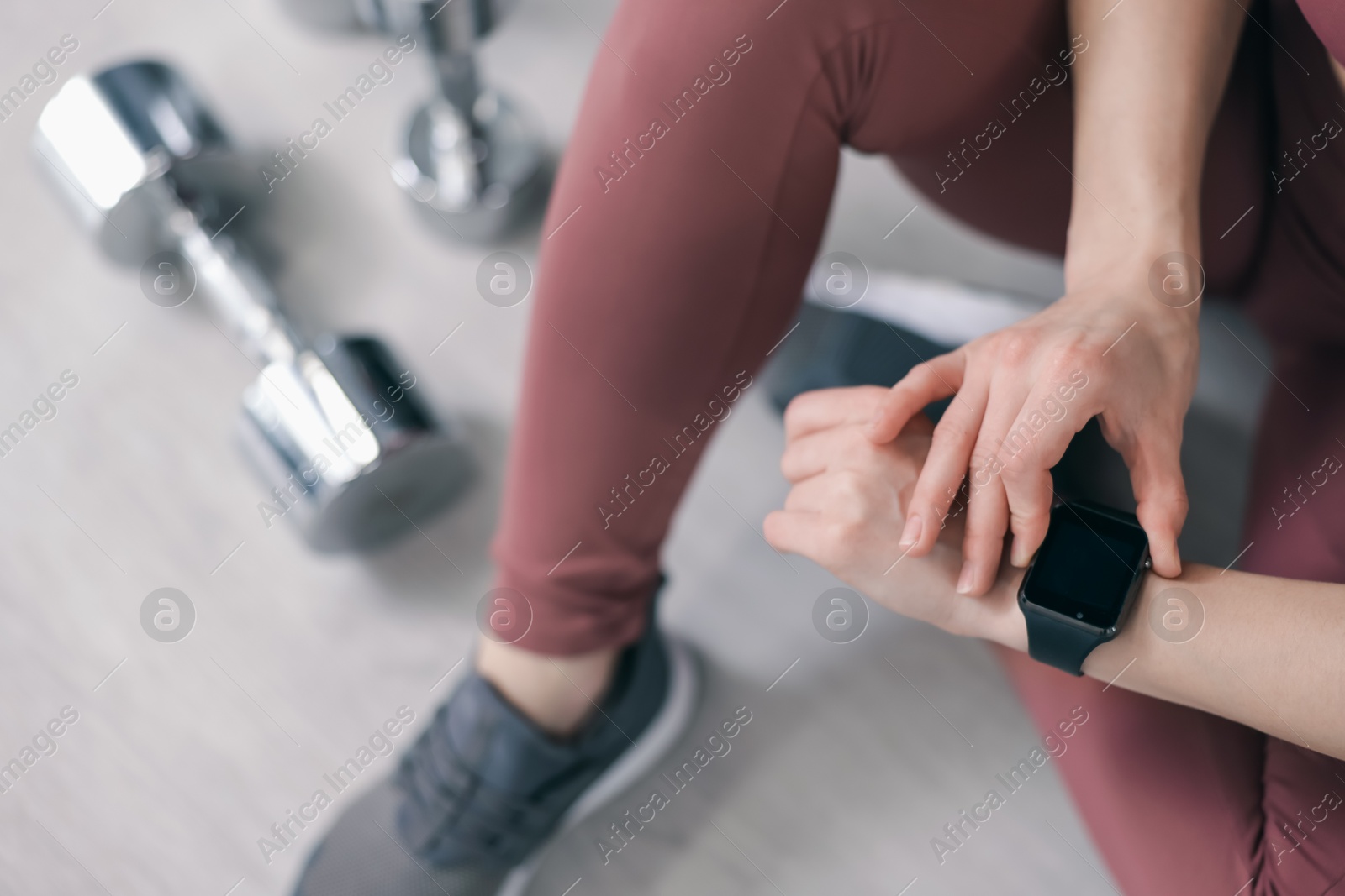 Woman checking fitness tracker during training indoors, above view Photo of Woman checking fitness tracker during training indoors, above view