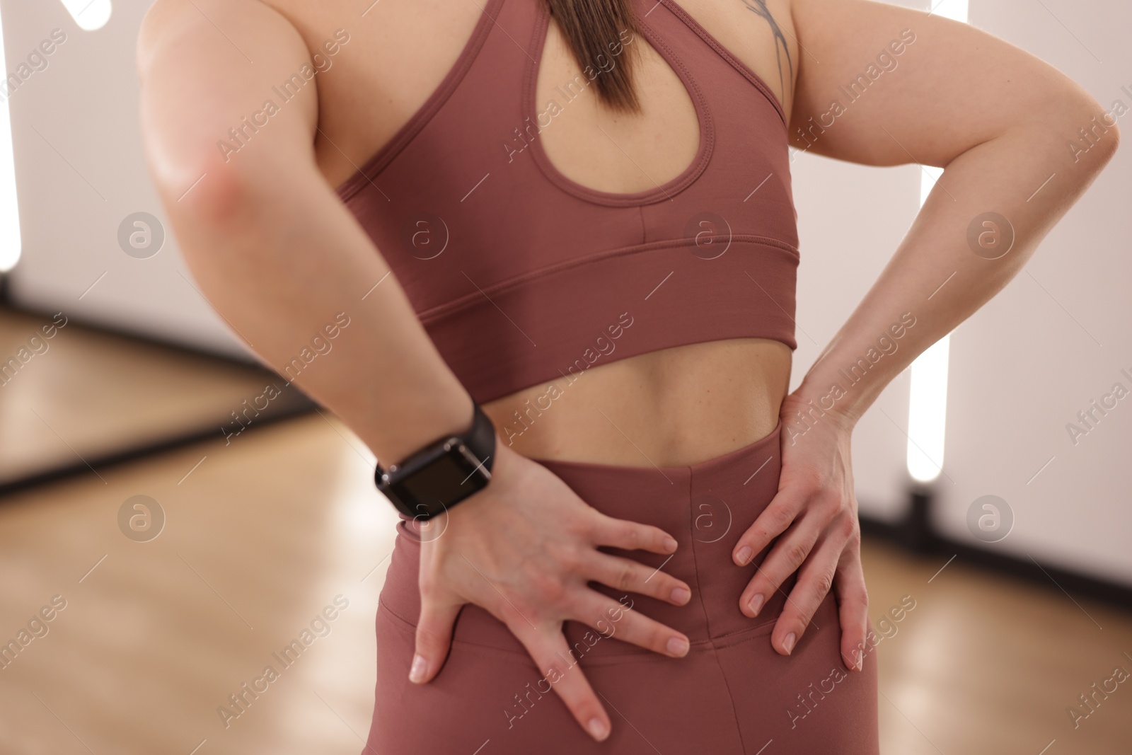 Sportswoman with back injury in fitness studio, closeup Photo of Sportswoman with back injury in fitness studio, closeup
