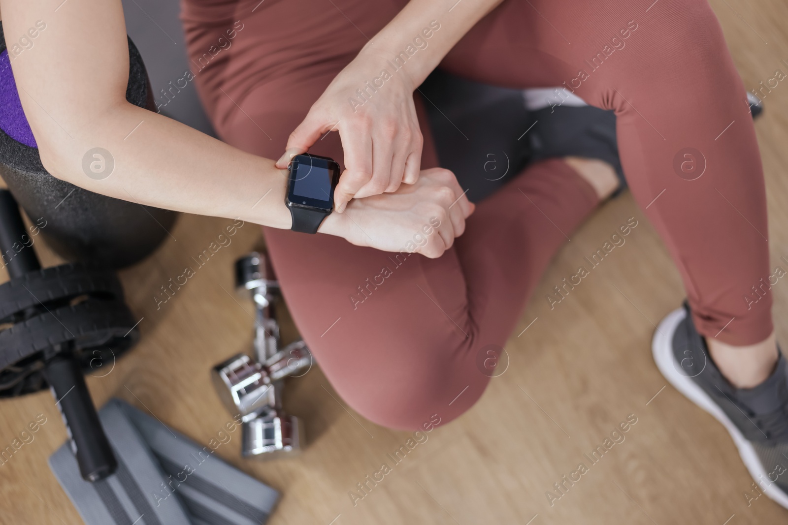 Woman checking fitness tracker during training indoors, top view Photo of Woman checking fitness tracker during training indoors, top view