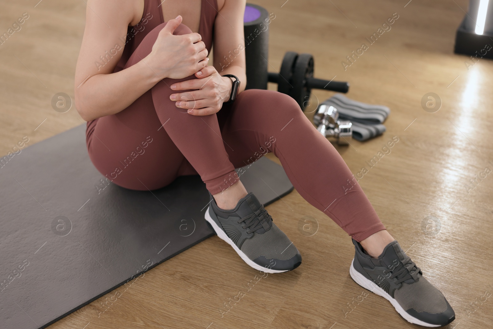 Sportswoman with leg injury suffering from knee pain in fitness studio, closeup Photo of Sportswoman with leg injury suffering from knee pain in fitness studio, closeup