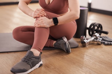 Photo of Sportswoman with leg injury suffering from knee pain in fitness studio, closeup
