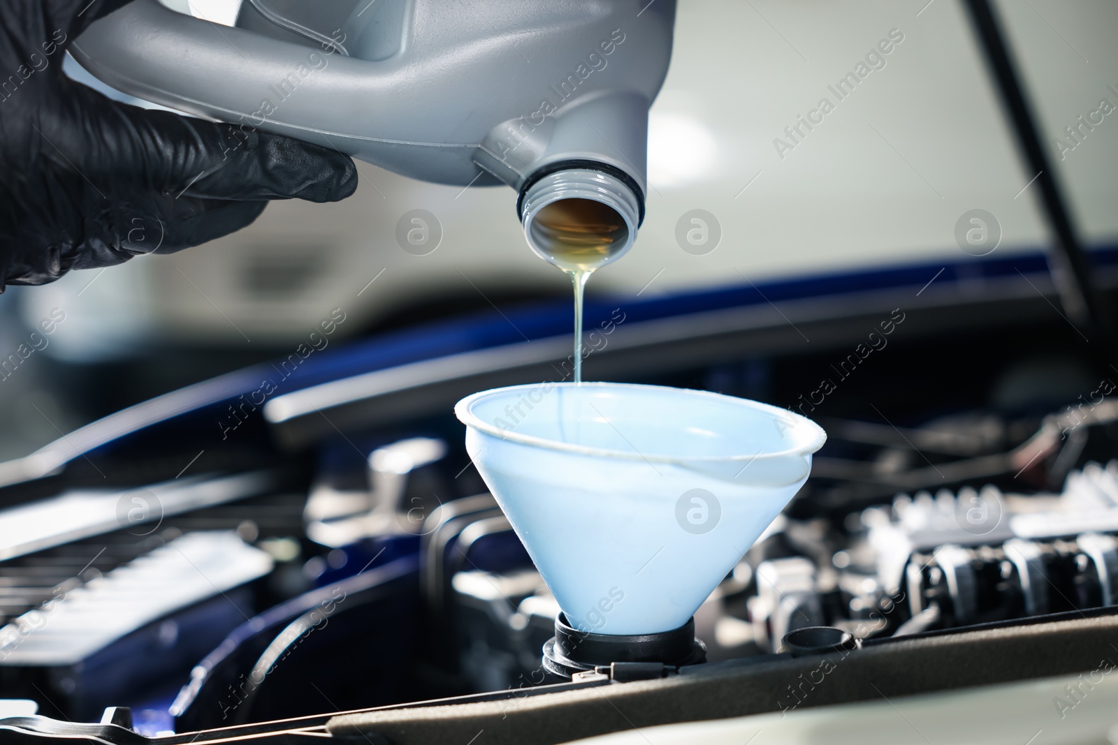 Worker pouring motor oil from canister into car engine, closeup Photo of Worker pouring motor oil from canister into car engine, closeup