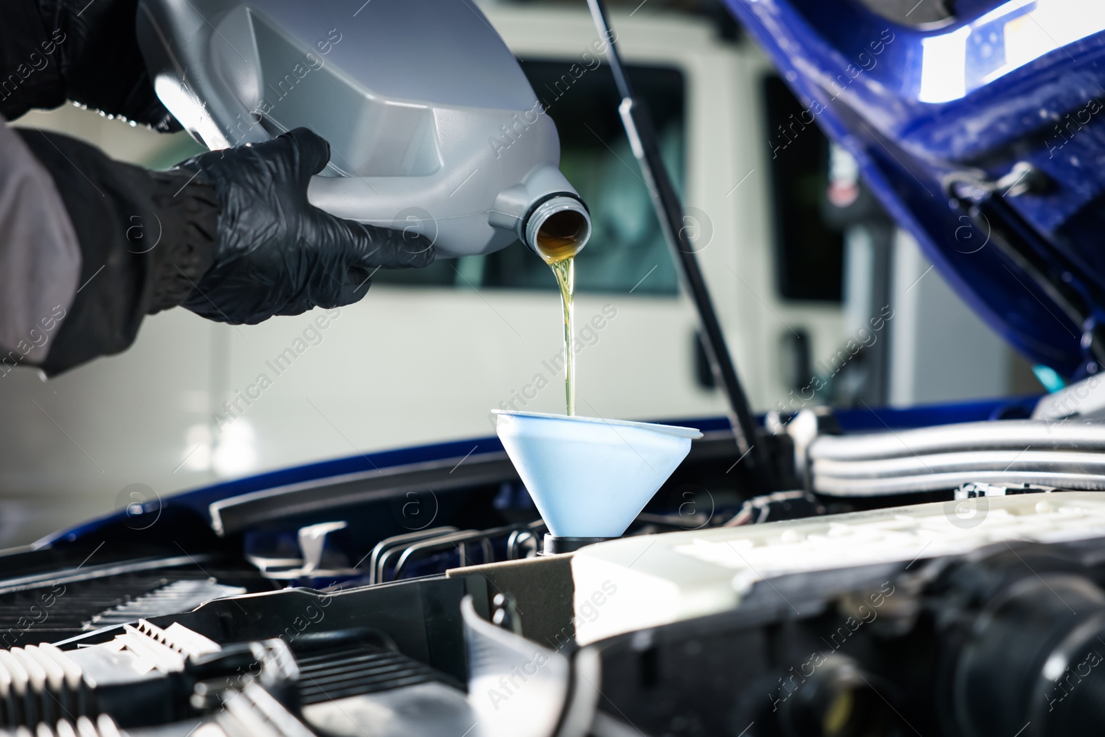 Worker pouring motor oil from canister into car engine, closeup Photo of Worker pouring motor oil from canister into car engine, closeup