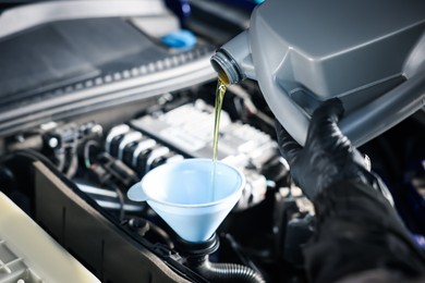 Photo of Worker pouring motor oil from canister into car engine, closeup