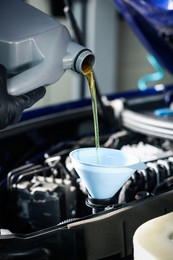 Photo of Worker pouring motor oil from canister into car engine, closeup
