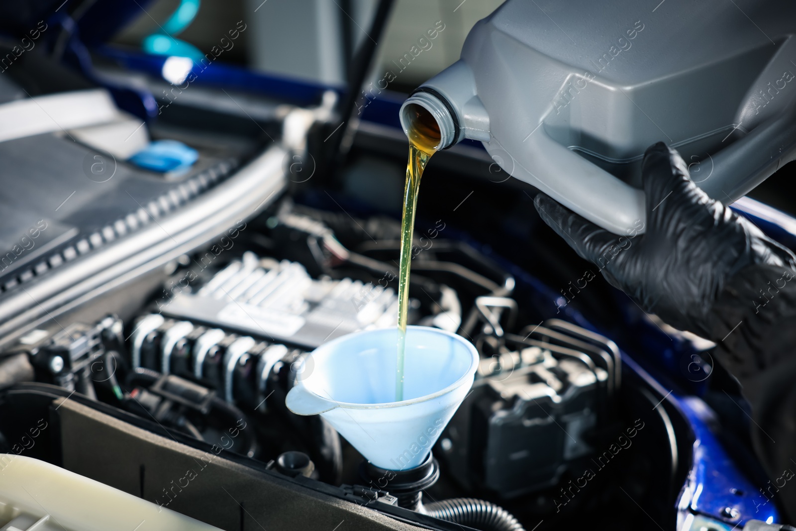 Worker pouring motor oil from canister into car engine, closeup Photo of Worker pouring motor oil from canister into car engine, closeup