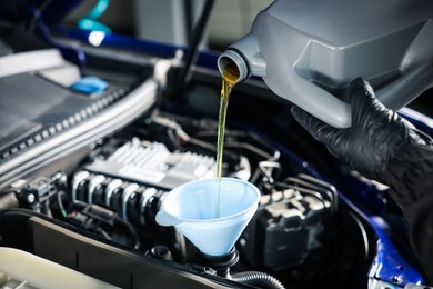 Photo of Worker pouring motor oil from canister into car engine, closeup
