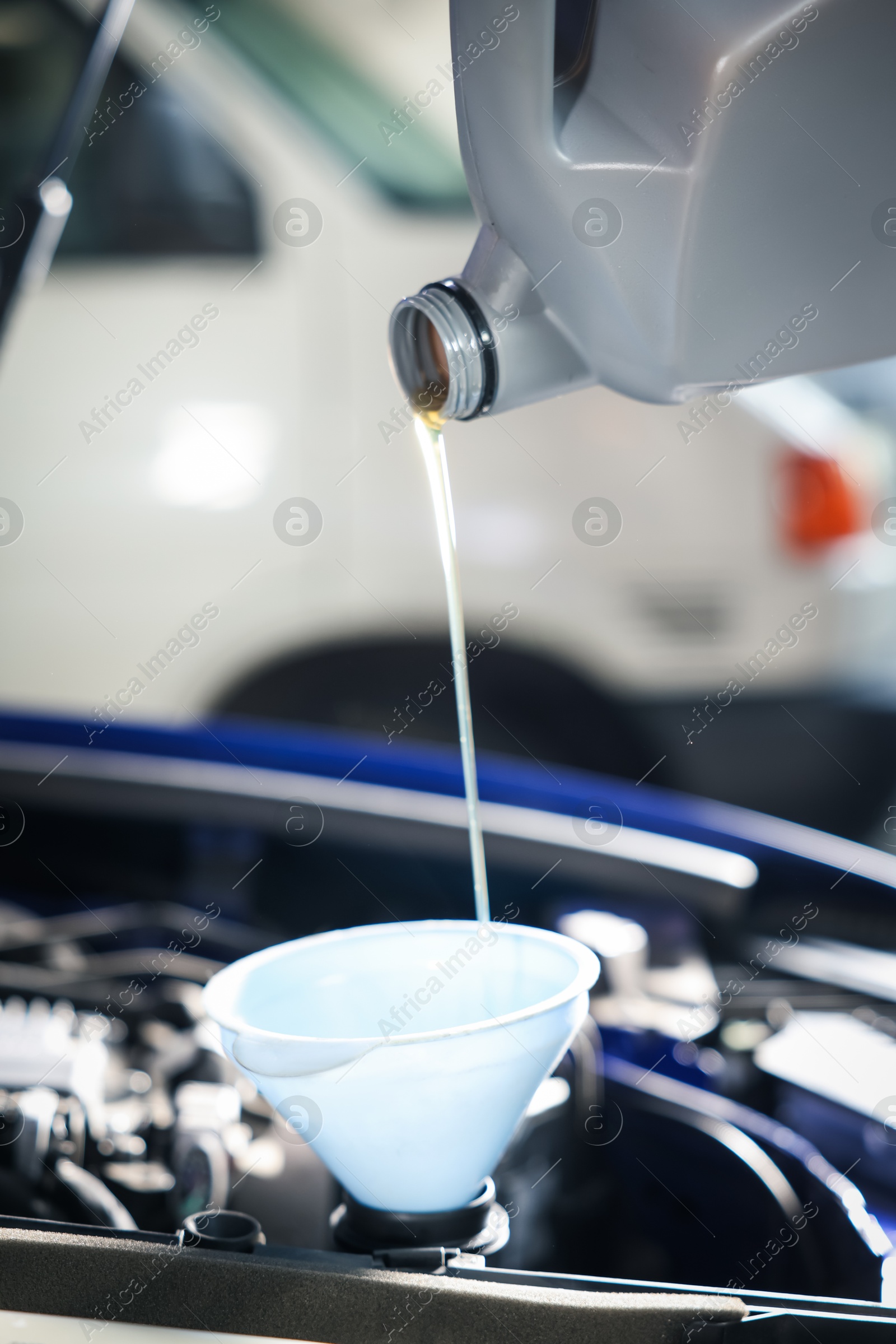 Pouring motor oil from bottle into car engine, closeup Photo of Pouring motor oil from bottle into car engine, closeup