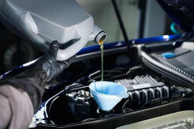 Photo of Worker pouring motor oil from canister into car engine, closeup