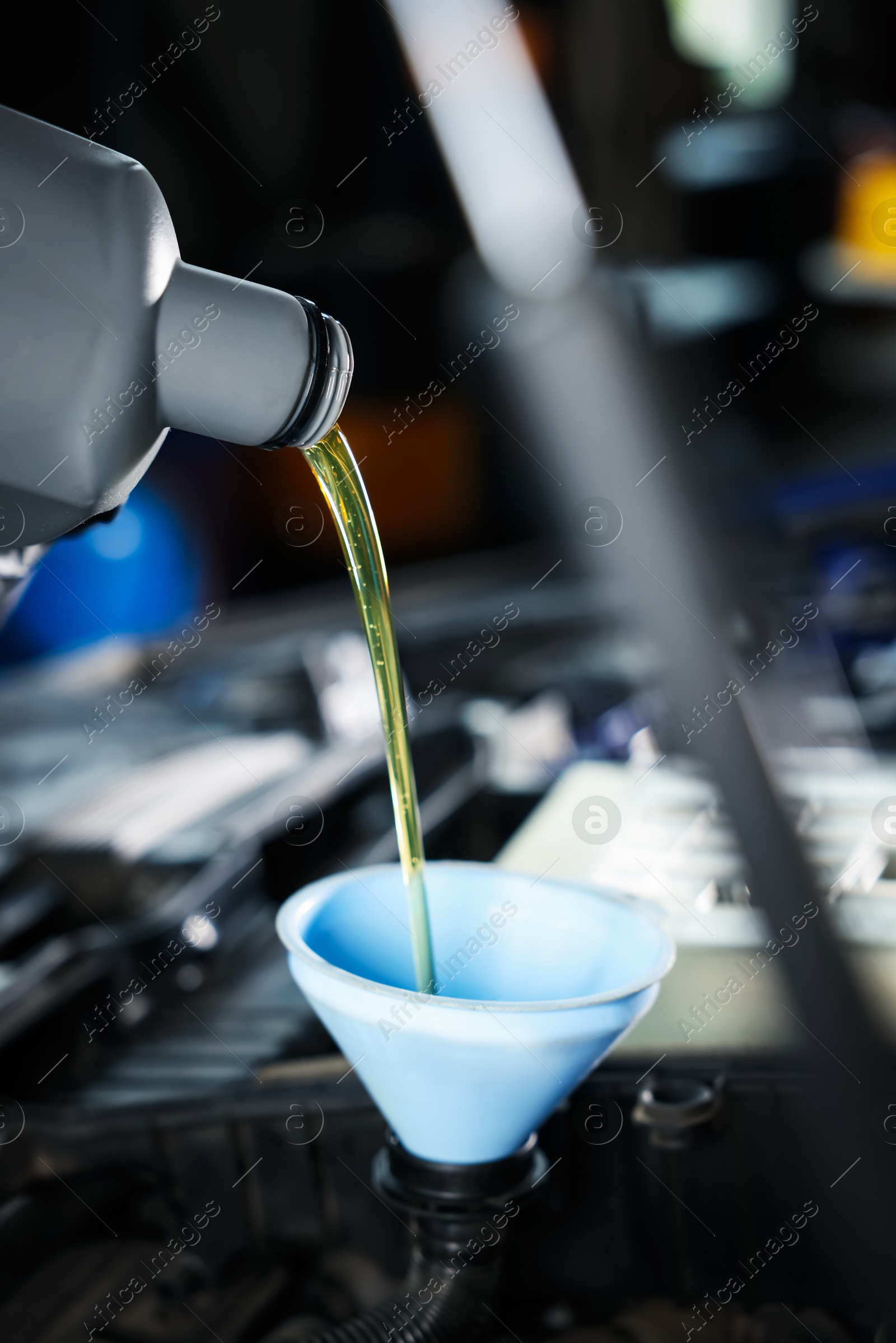 Pouring motor oil from bottle into car engine, closeup Photo of Pouring motor oil from bottle into car engine, closeup
