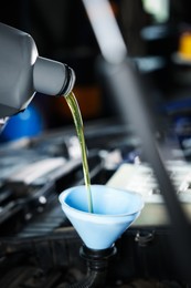 Photo of Pouring motor oil from bottle into car engine, closeup